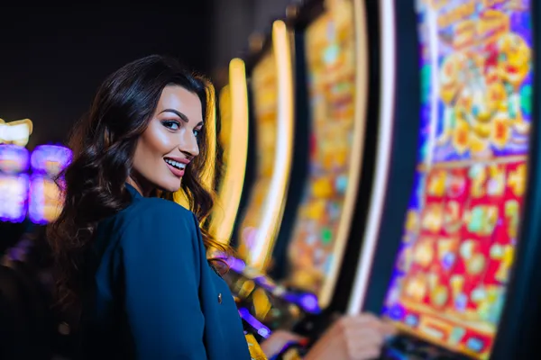 A woman smiling by bright slot machines showing lucky symbols, showcasing the exciting slot offerings at BDJL1.
